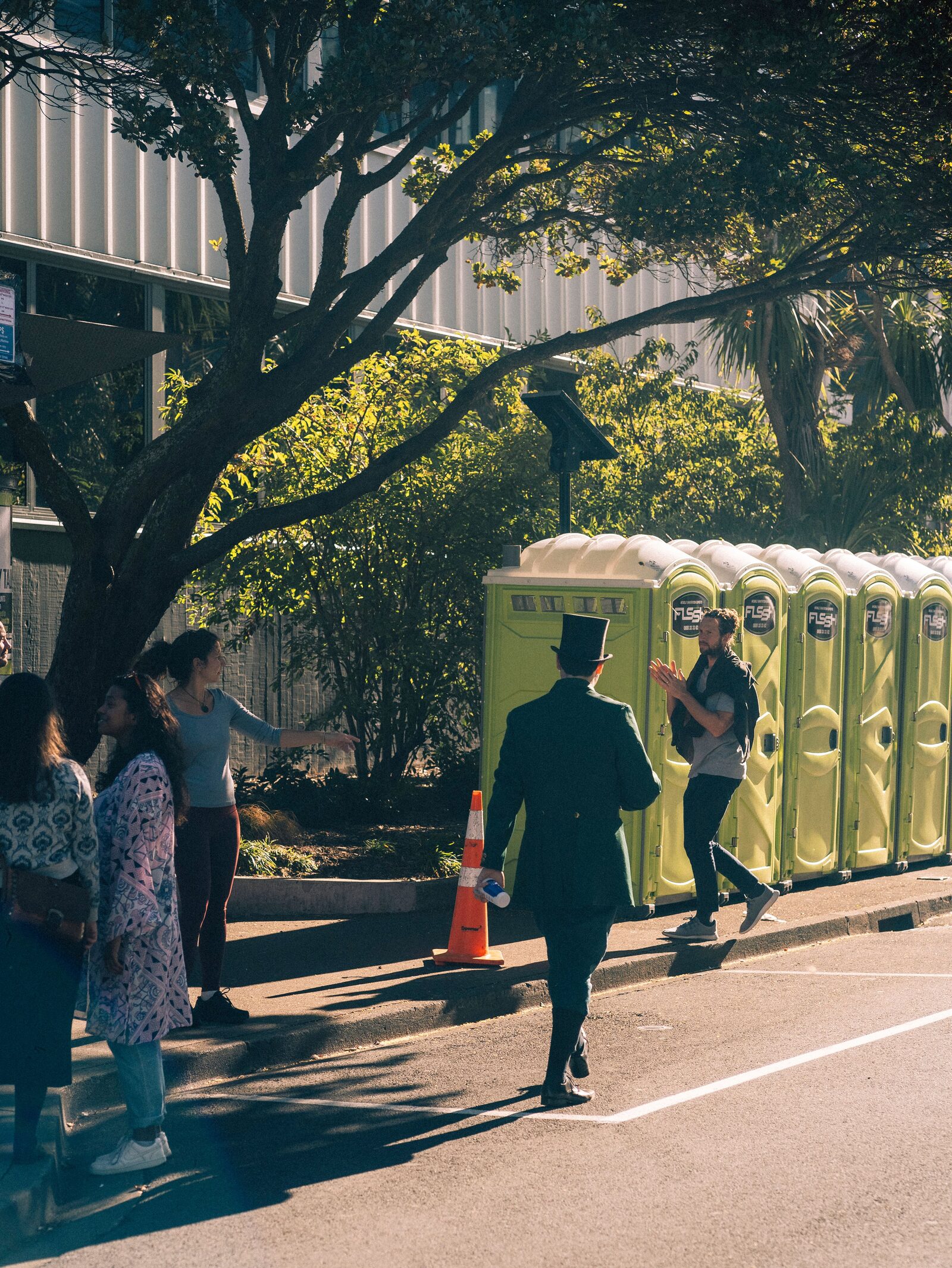Row of standard portable toilets set up along a public sidewalk